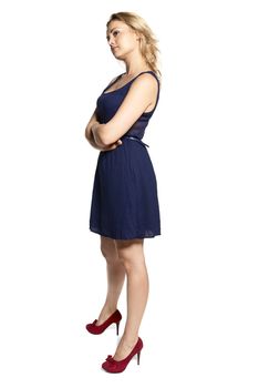 Studio shot of attractive young offended woman in blue dress and red high heels isolated on white background. 