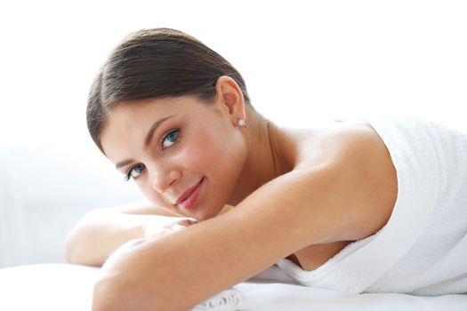 Happy beautiful young woman on massage table isolated on white