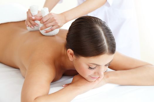 Woman in spa getting massage with herbal balls