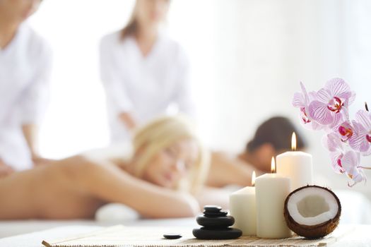 Spa massage tools and women getting massage on background