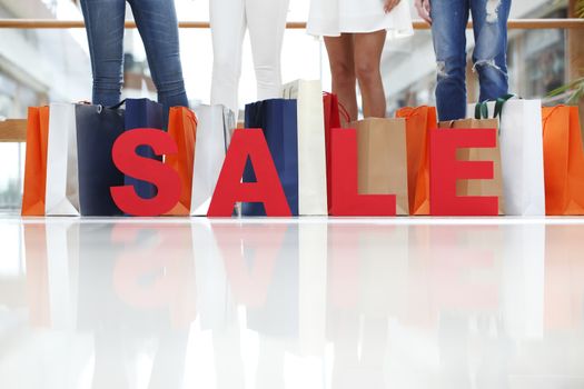 Women with red sale letters in mall, shopping concept