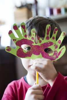 portrait of a 6 year old boy with a carnival mask made by himself at home