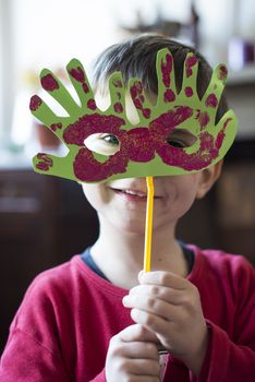 portrait of a 6 year old boy with a carnival mask made by himself at home