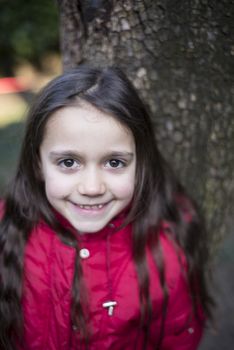 portrait of 7 year old girl in outdoor in the garden in winter with red jacket