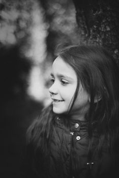 portrait of 7 year old girl in outdoor in the garden in winter with red jacket