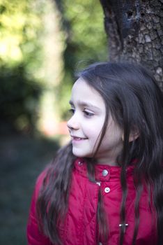 portrait of 7 year old girl in outdoor in the garden in winter with red jacket