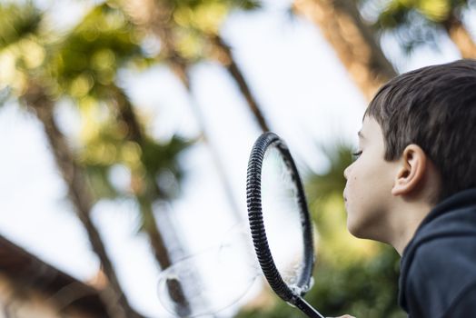 7-year-old child outdoors in the garden in winter makes big soap bubbles