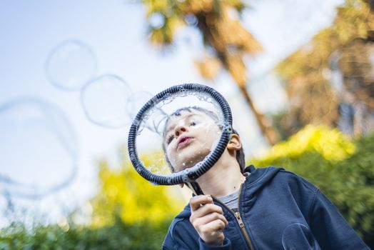 7-year-old child outdoors in the garden in winter makes big soap bubbles