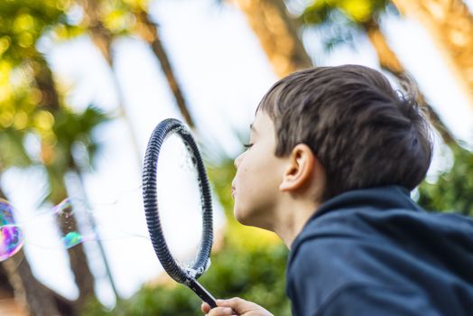 7-year-old child outdoors in the garden in winter makes big soap bubbles