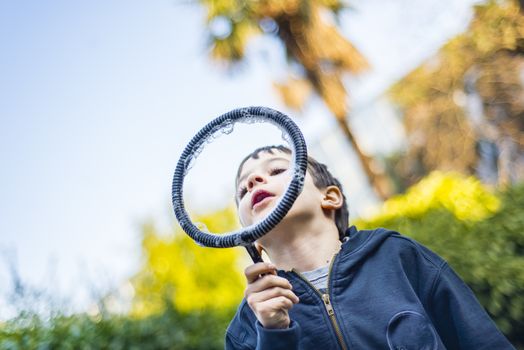 7-year-old child outdoors in the garden in winter makes big soap bubbles