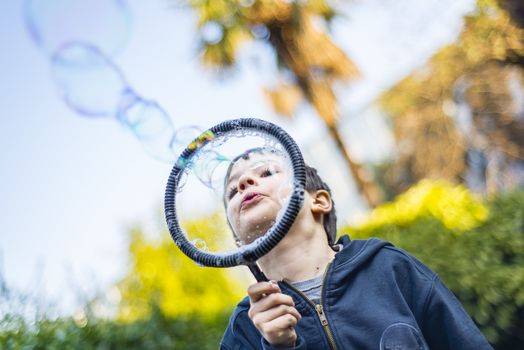 7-year-old child outdoors in the garden in winter makes big soap bubbles