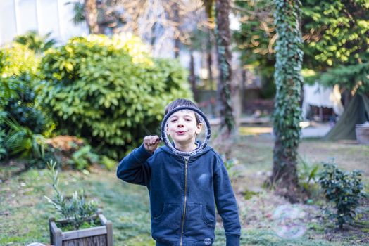 7-year-old child outdoors in the garden in winter makes big soap bubbles