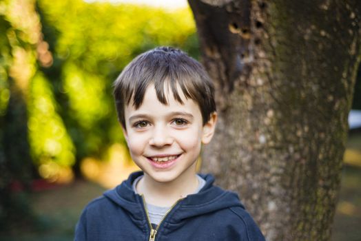 portrait of 7 year old boy outdoor in the garden in winter