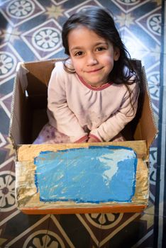 5-year-old girl plays with a self-made cardboard car, at home in her pajamas in the morning
