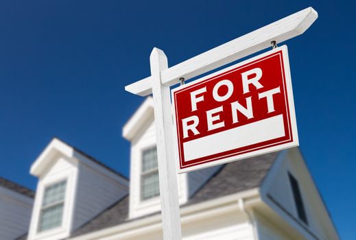 Right Facing For Rent Real Estate Sign In Front of House and Deep Blue Sky.