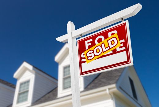 Right Facing Sold For Sale Real Estate Sign In Front of House and Deep Blue Sky.