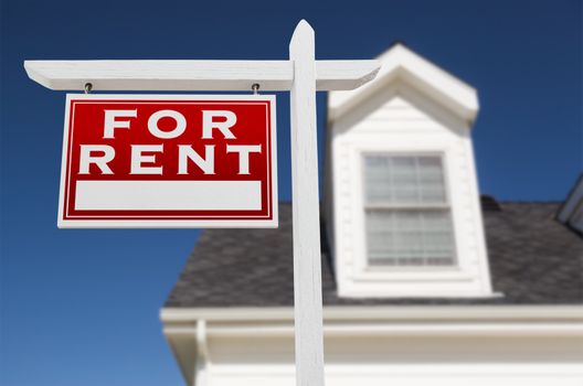 Left Facing For Rent Real Estate Sign In Front of House and Deep Blue Sky.