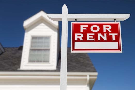 Right Facing For Rent Real Estate Sign In Front of House and Deep Blue Sky.