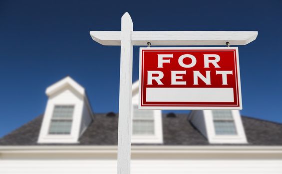 Right Facing For Rent Real Estate Sign In Front of House and Deep Blue Sky.