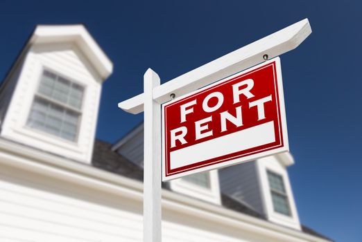 Right Facing For Rent Real Estate Sign In Front of House and Deep Blue Sky.