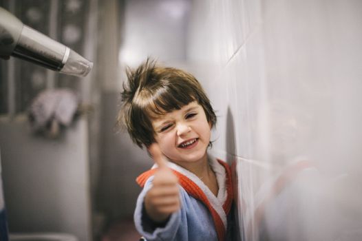 mother dries her son's hair with the hair dryer after the bath