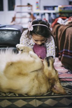 little girl at home with her golden retriever dog have affectionate gestures