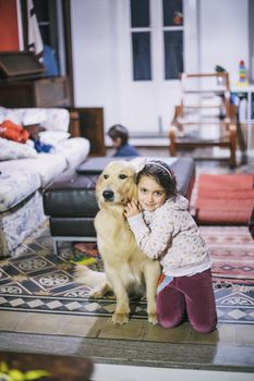 little girl at home with her golden retriever dog have affectionate gestures