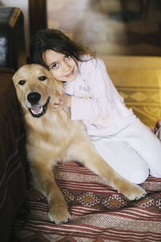 little girl at home with her golden retriever dog have affectionate gestures