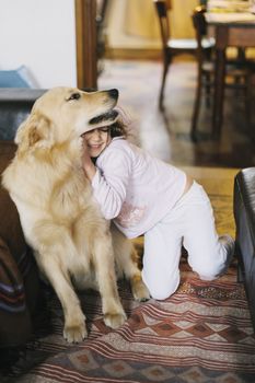 little girl at home with her golden retriever dog have affectionate gestures