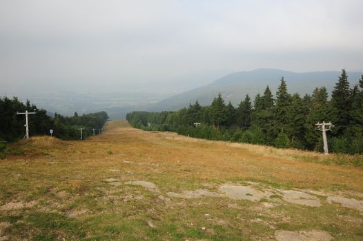 Panorama of beautiful green landscapes in the mist and rain with ski slope