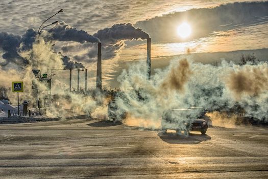 cars on the background of smoke from factories winter day steam from cold