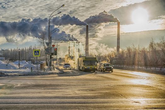 cars on the background of smoke from factories winter day steam from cold