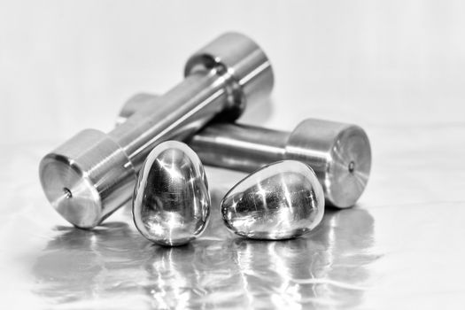 Metal dumbbells and steel eggs, the concept of sports training and the achievement of muscle strength.