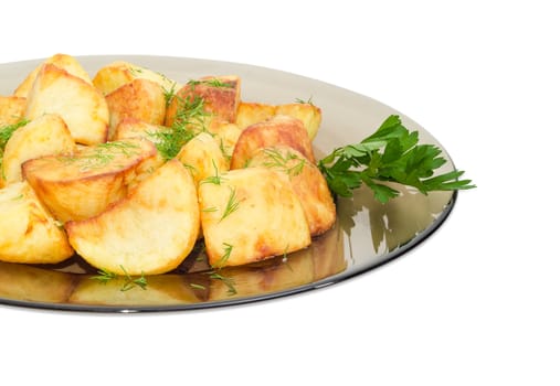 Fragment of the dark glass dish with fried potatoes sprinkled by chopped dill and twig of parsley on a light background
