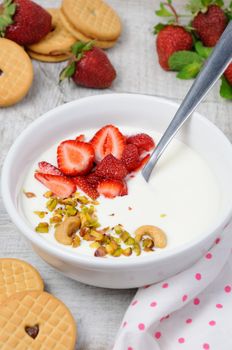 Chilled Buttermilk soup from Greek yogurt with strawberries and pistachios, cashews. Serve with crispy biscuits. Vertical shot.