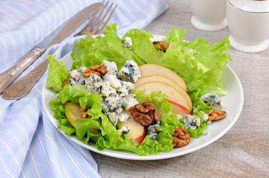 A light lettuce salad with pear slices, gorgonzola pieces and walnut seasoned with olive oil