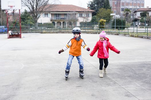 children, brother and sister, skate in the basketball field on a winter day