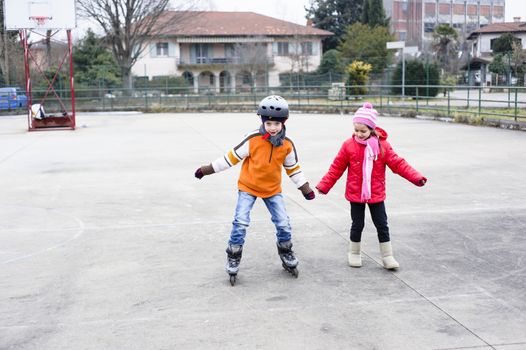 children, brother and sister, skate in the basketball field on a winter day