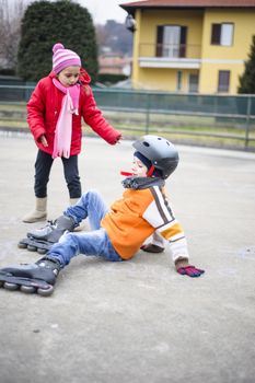 children, brother and sister, skate in the basketball field on a winter day
