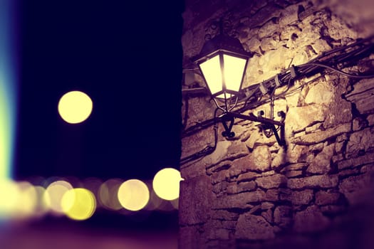 City lights and lamppost in the facade.Stone wall background at night