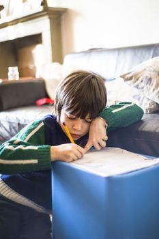 6-year-old boy writes on a sheet in his house by day
