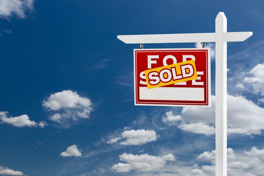 Left Facing Sold For Sale Real Estate Sign Over Blue Sky and Clouds With Room For Your Text.