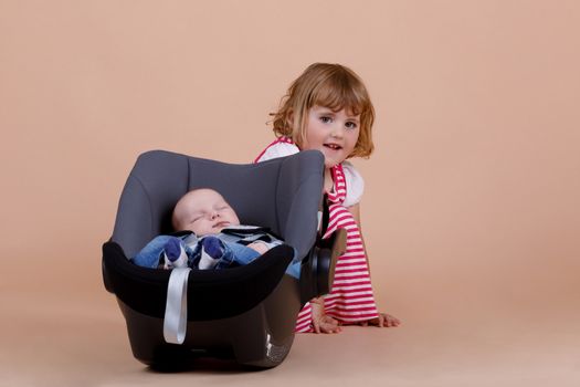 studio portrait of young cute baby girl with infant brother on beige background