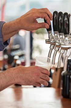 Barman pouring a fresh beer in a glass