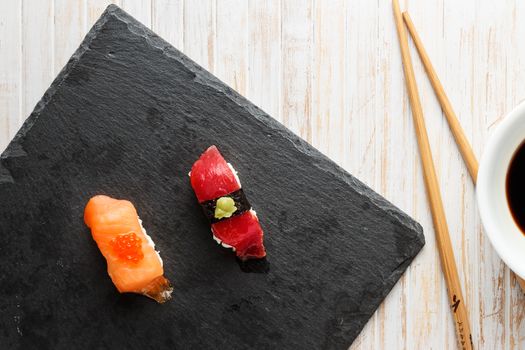 Salmon Nigiri with Salmon Roe and red tuna with wasabi paste Nigiri on black slate stone seen from above. Raw fish in traditional Japanese sushi style. Horizontal image.