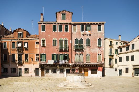 Old buildings and square with a well in Venice, Italy