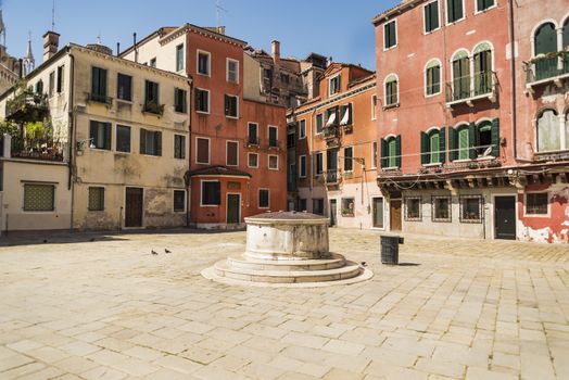 Old buildings and square with a well in Venice, Italy