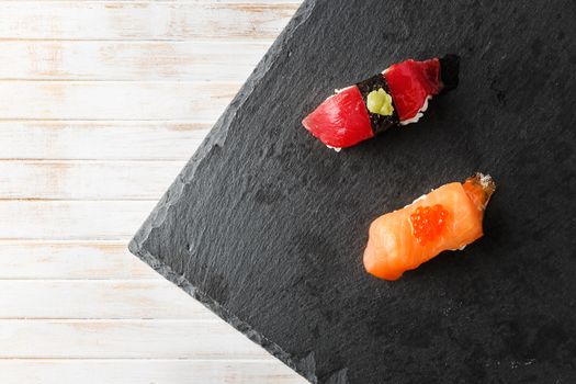 Salmon Nigiri with Salmon Roe and red tuna with wasabi paste Nigiri on black slate stone seen from above. Raw fish in traditional Japanese sushi style. Horizontal image.