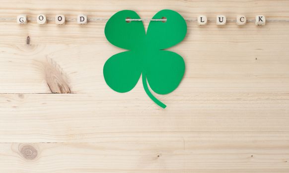 The words Good Luck and a cloverleaf on a cord on wood