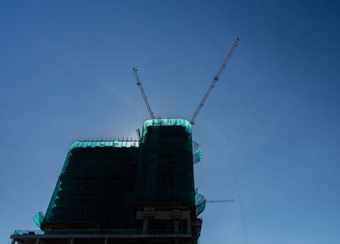 Cranes in operation over a construction site with clear blue skies in Vietnam.